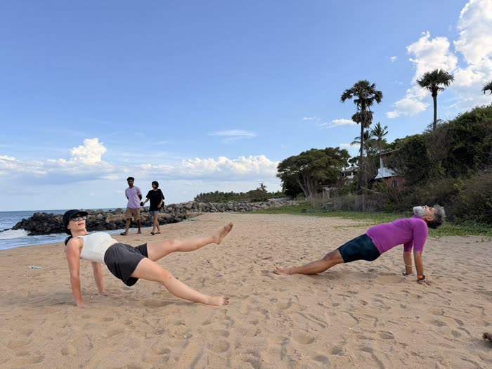 A client lifting one leg in a reverse plank as Rotem holds the pose alongside