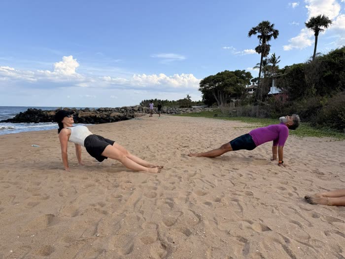 Rotem and a client holding reverse-plank holds side by side on the beach
