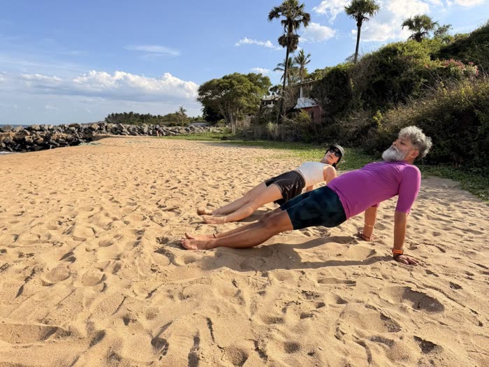 Rotem and a client pressing into reverse planks on the beach