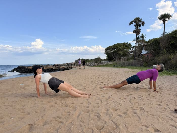 Rotem and a client in reverse planks across the sand at golden hour