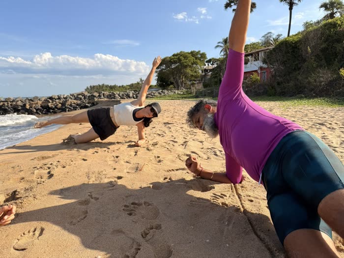 Rotem and a client doing side planks together by the shoreline