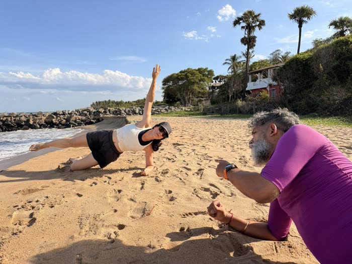 A client in a side plank reaching skyward while Rotem coaches her form