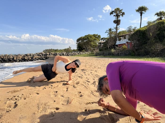 A client steadying a side plank while Rotem checks her alignment